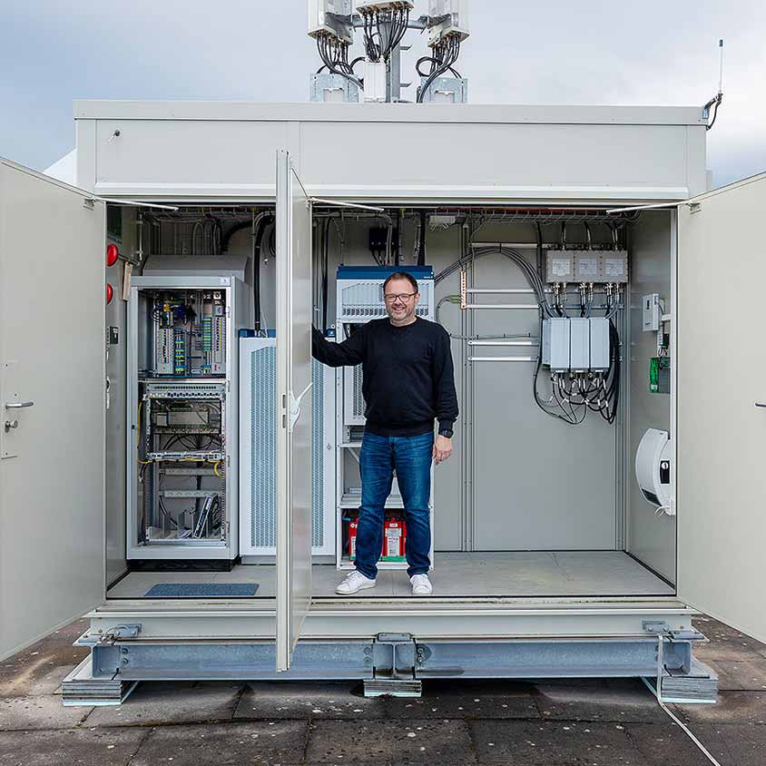 Infravista - A man standing in front of a large equipment room for mobile antenna technology
